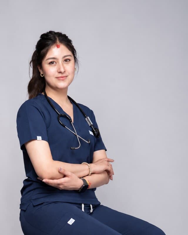 Nurse in a navy Medisewa scrub top with an embroidered badge